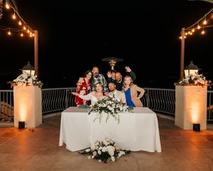Evening outdoor wedding reception with string lights and guests seated at decorated tables.