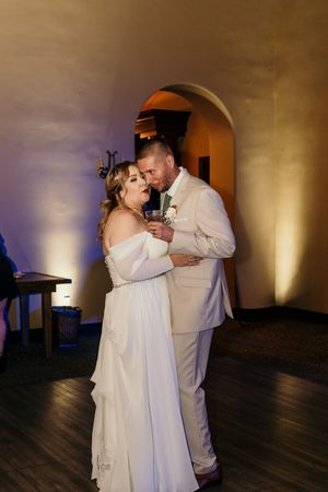 Romantic first dance sequence between newlyweds on a dark wooden dance floor.
