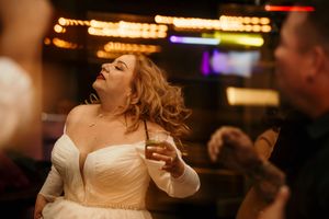 A bride dances joyfully under colorful lights at her wedding reception.