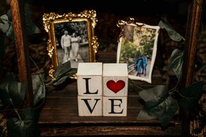 Rustic wedding decor spells out 'LOVE' with wooden blocks and heart symbol against a dark background.