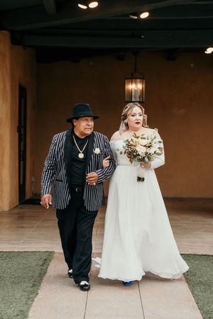 A sweet moment captured during a wedding walk with a bride in white dress and companion in striped vest.