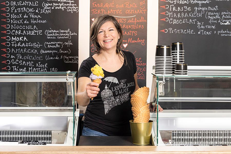 Ice cream being served behind a counter with menu items written on chalkboards.