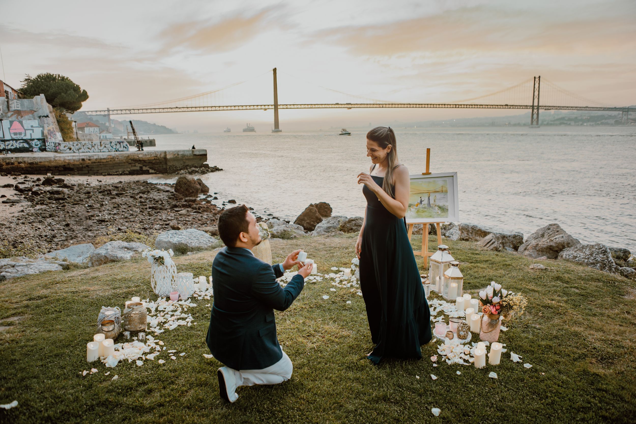 Couple enjoying a romantic sunset picnic overlooking the Golden Gate Bridge with candles and wine.