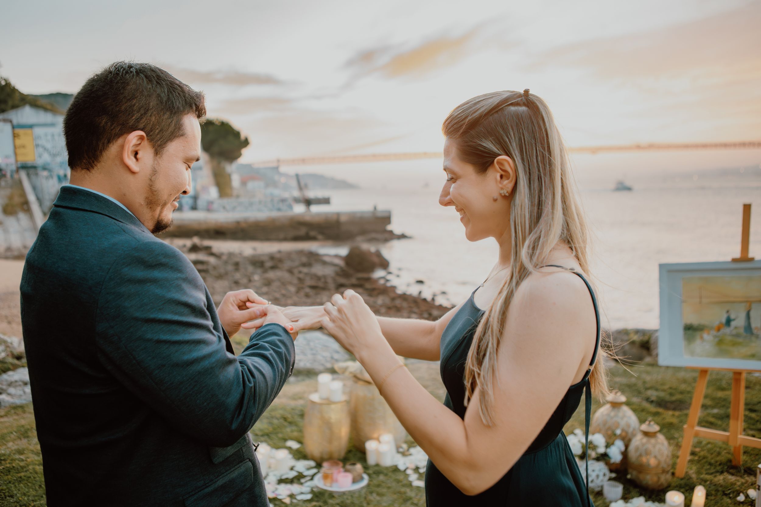 Romantic couple dances together on coastal cliffside at sunset surrounded by flowers and decor.