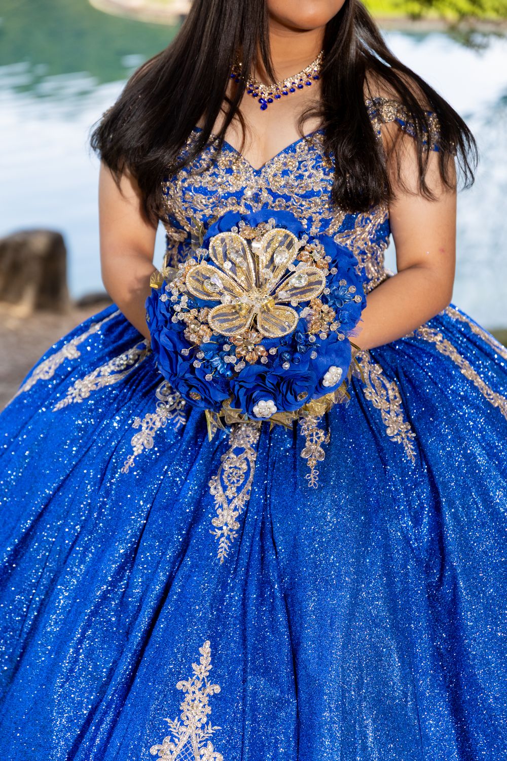 Close-up of a sparkling royal blue quinceañera dress with intricate silver embellishments and a matching bouquet.