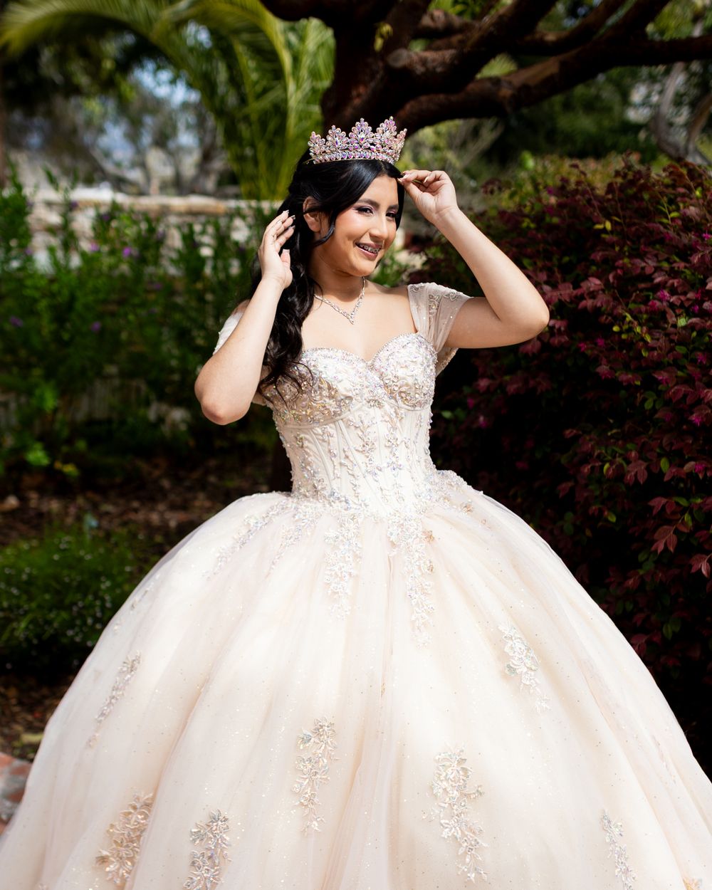 A white ballgown wedding dress with lace details and beading sparkles in an outdoor garden setting.