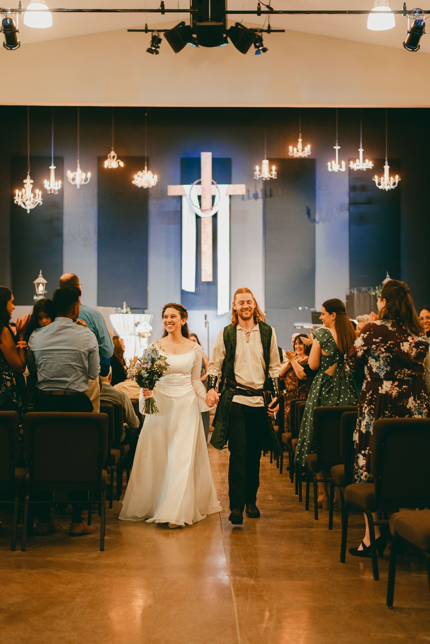 Bride and groom walking down aisle together happily holding hands, now married