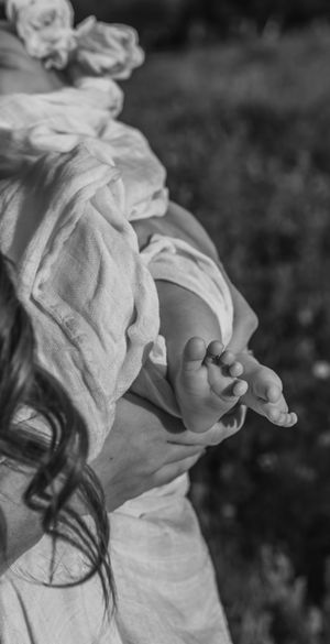 Close-up black and white image of a baby's tiny hand reaching out towards sunlight.