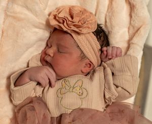 Newborn baby sleeping peacefully wrapped in soft pink blankets.