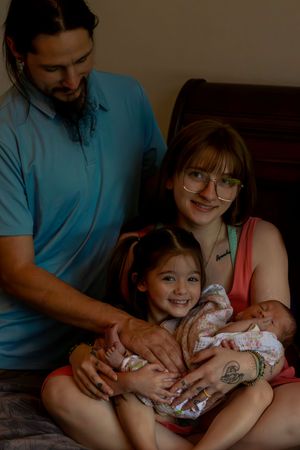 A family shares an intimate moment with their newborn baby while sitting together indoors.