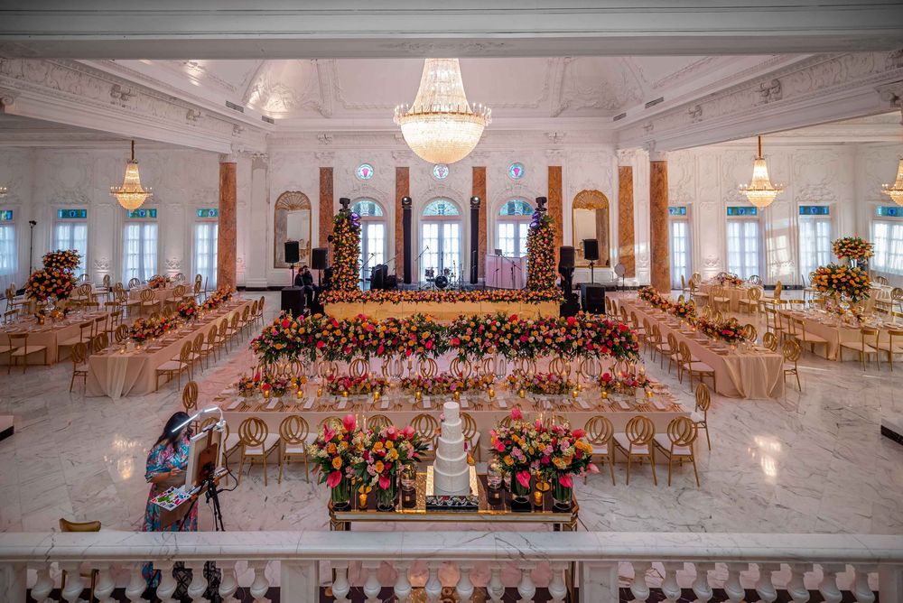 Elegant ballroom setup with crystal chandeliers, round tables, and a stunning floral head table arrangement.