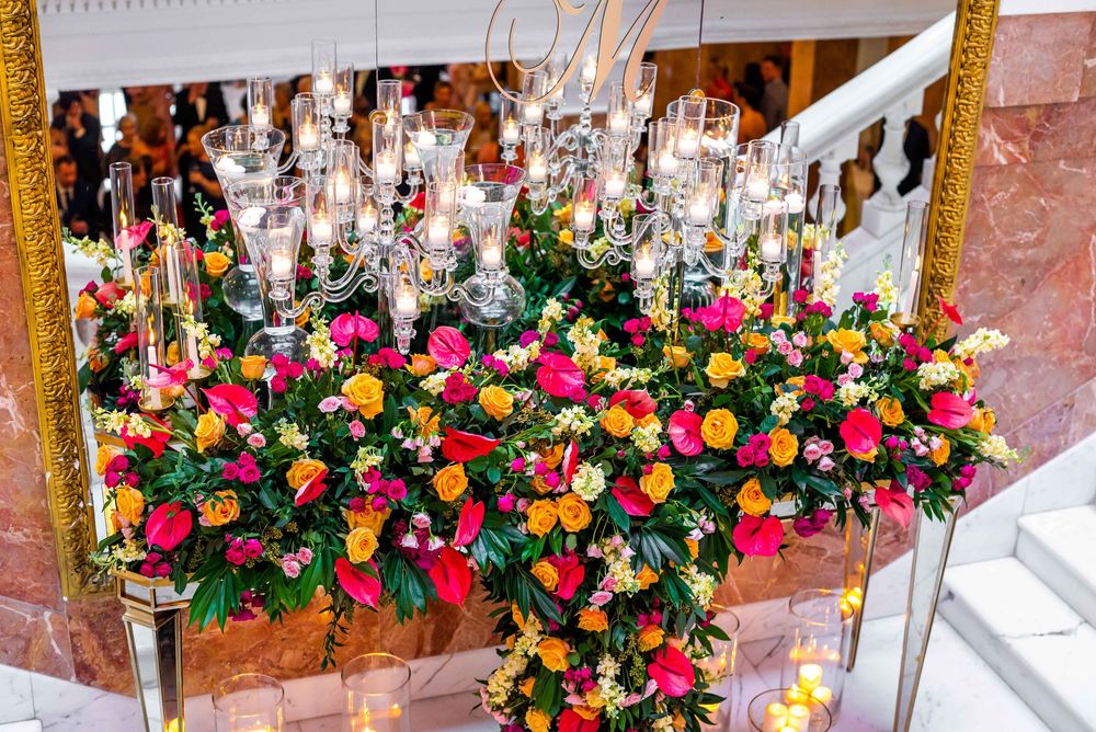 Colorful floral display with vibrant pink, yellow and orange blooms cascading from a wall-mounted arrangement.