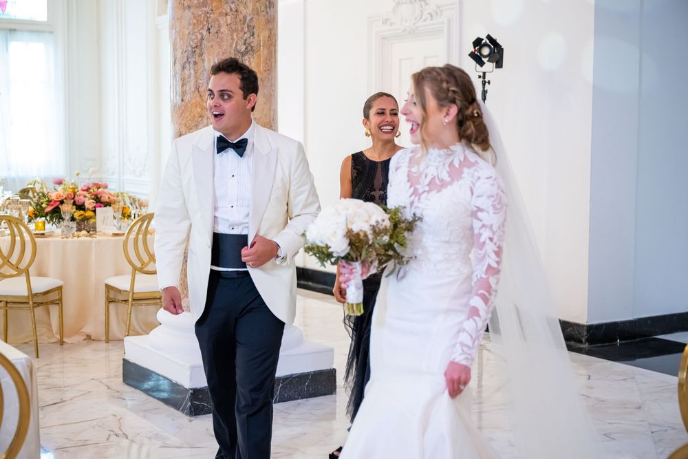 Wedding celebration in white marble venue with decorated reception tables and elegant decor.