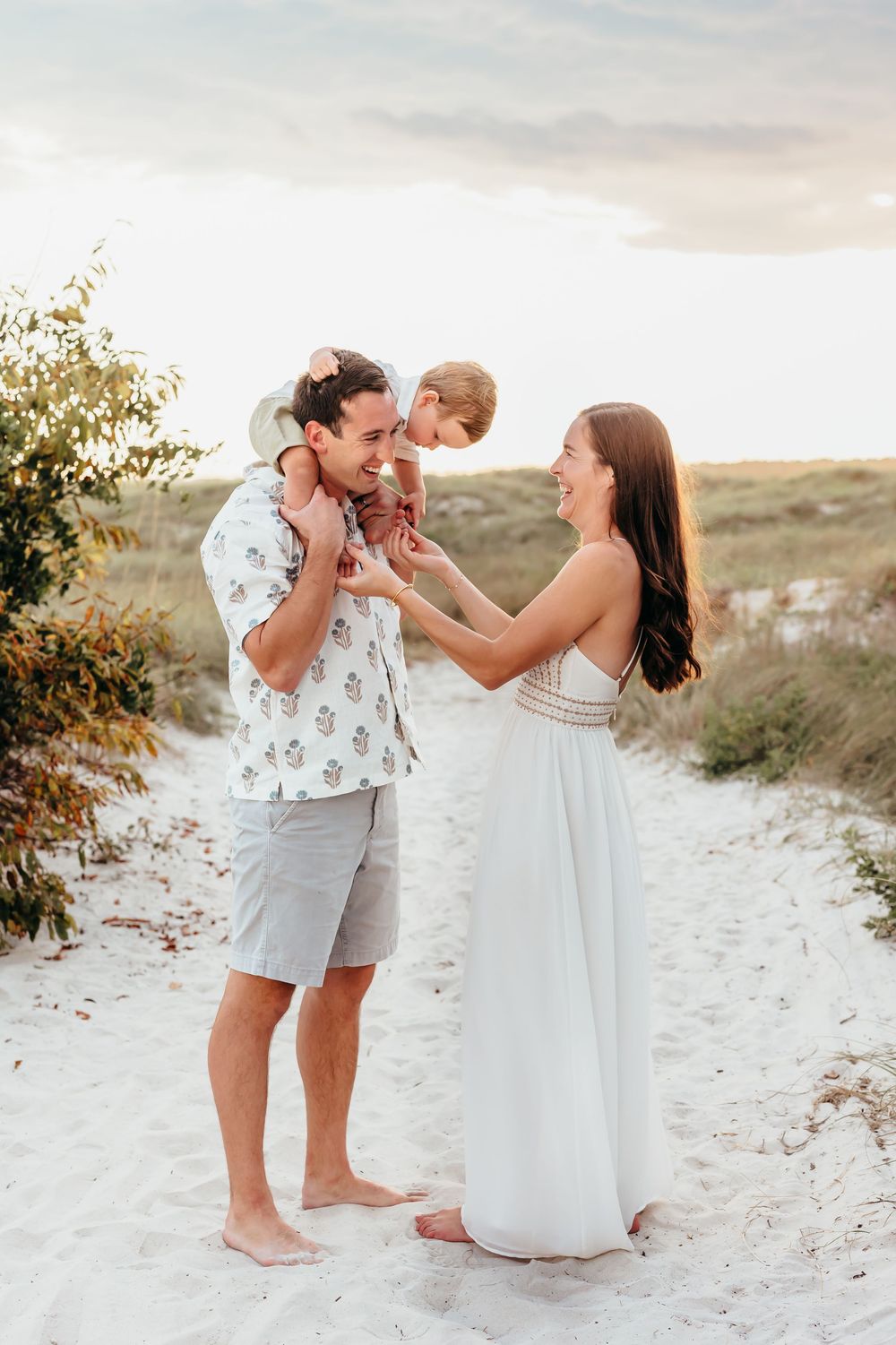 Family enjoying a tender moment together on sandy dunes at sunset.