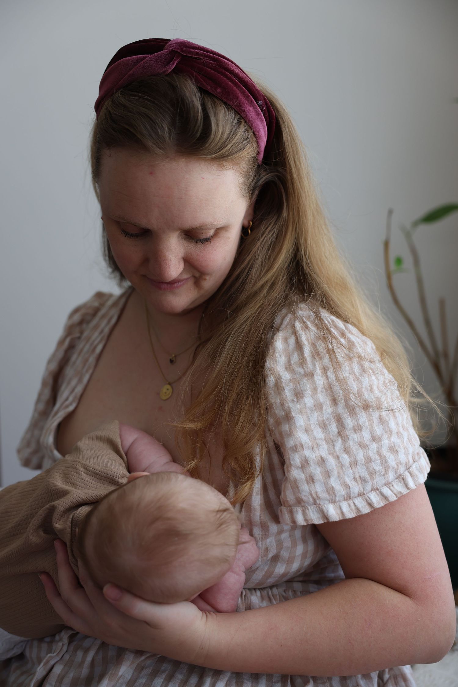 A caregiver with curly brown hair holds and comforts a baby wearing a white cloth diaper.