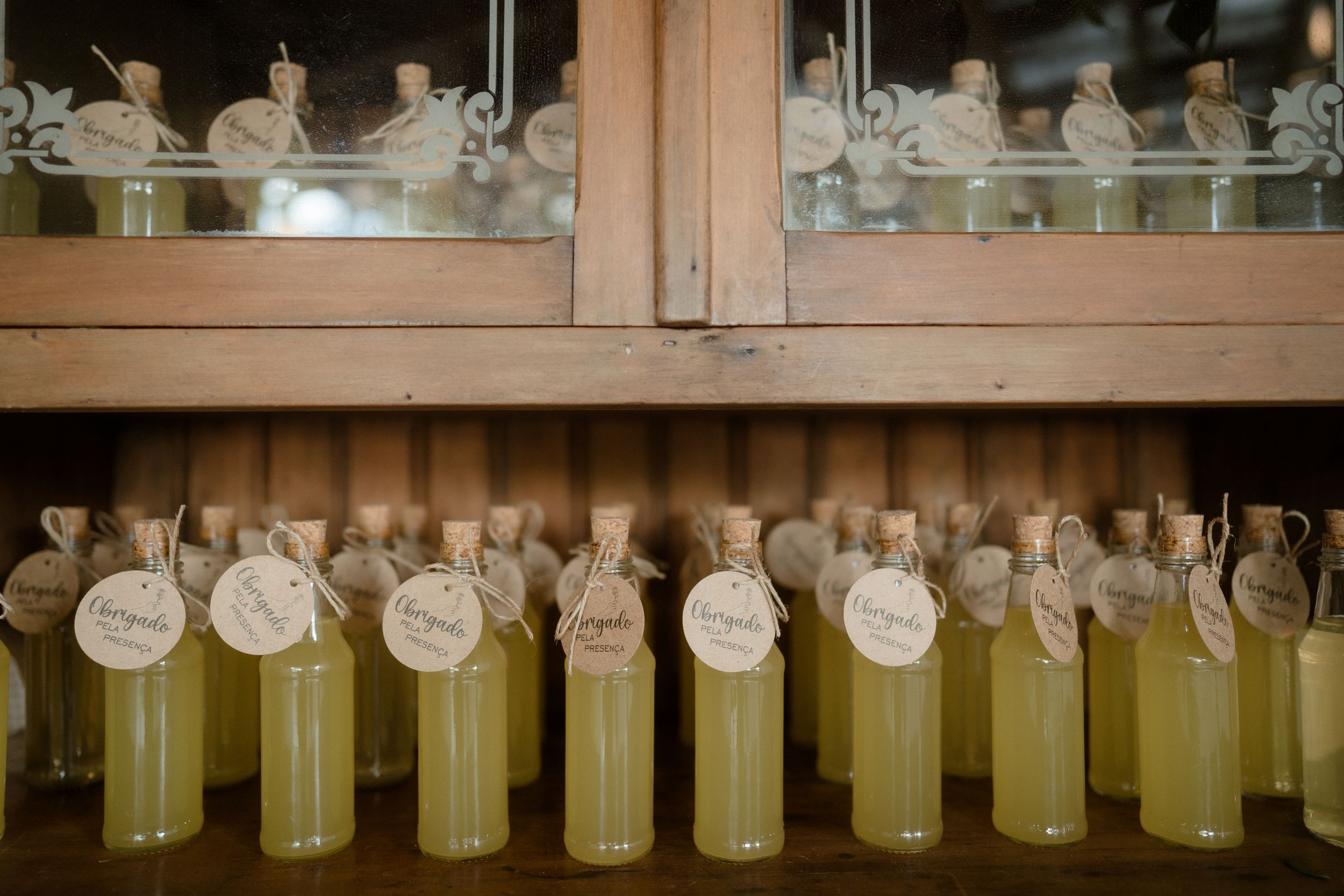 Glass bottles filled with yellow liquid arranged in rows inside a wooden cabinet.