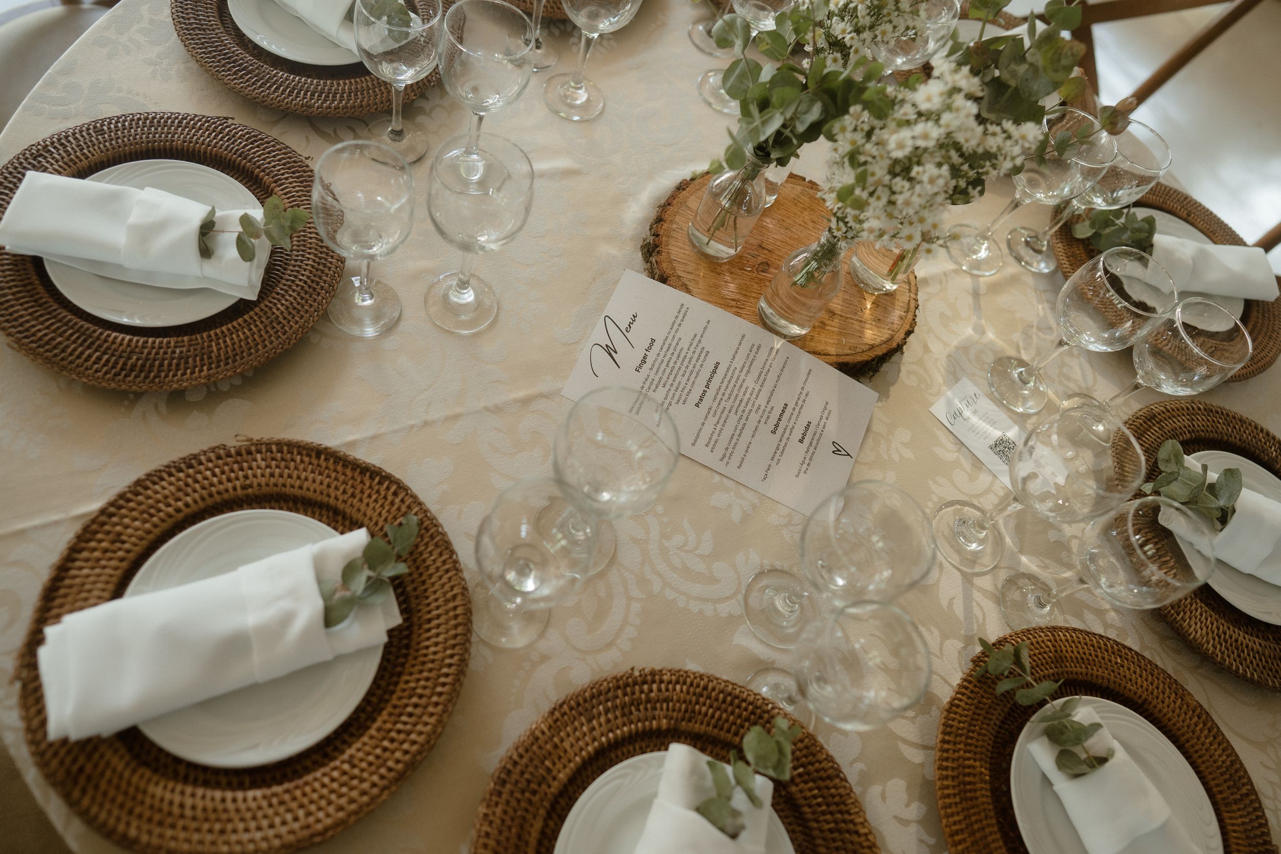 Elegant table setting with woven charger plates, white napkins, and delicate floral centerpieces.