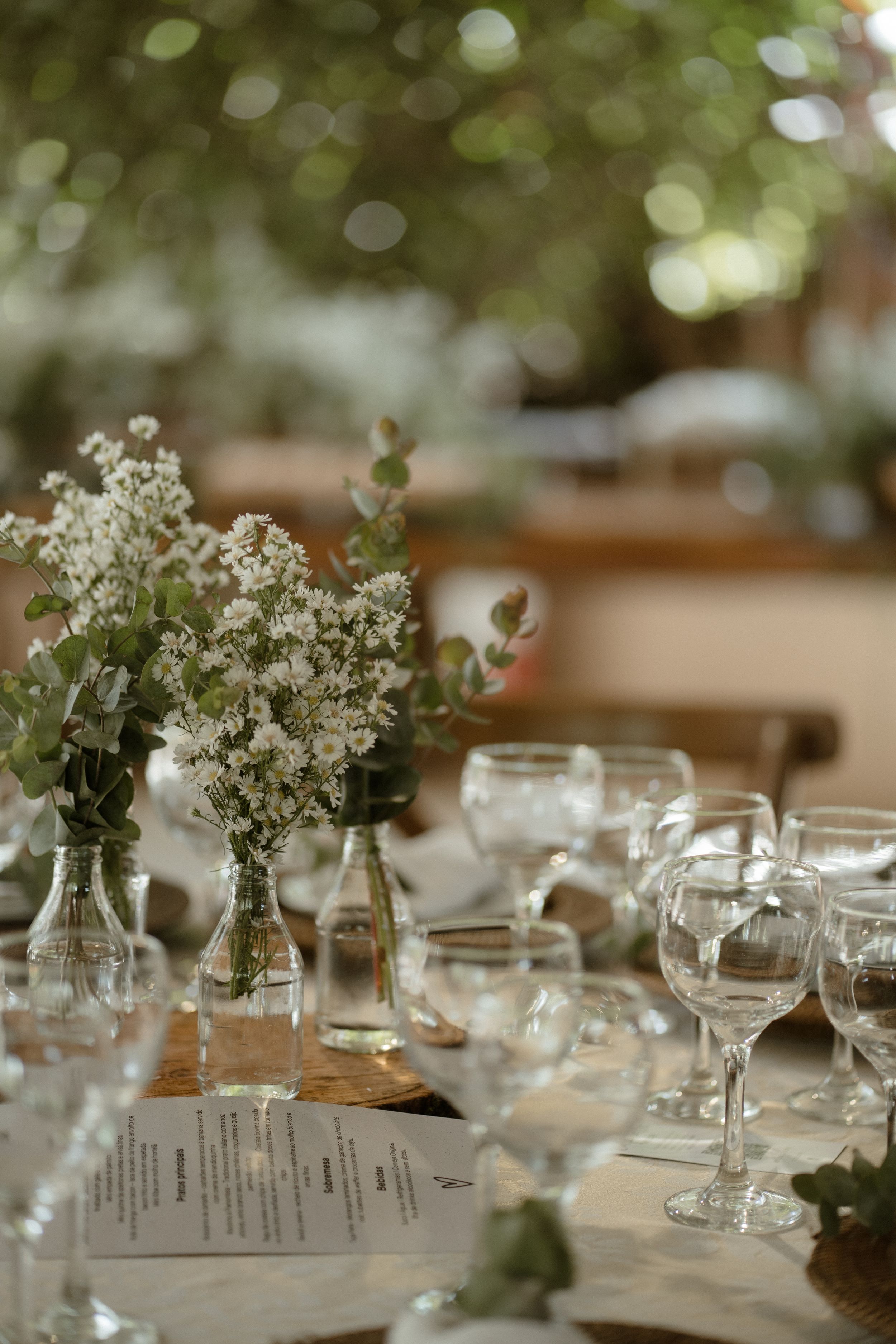 White baby's breath flowers in glass vases on an elegant table setting with wine glasses.
