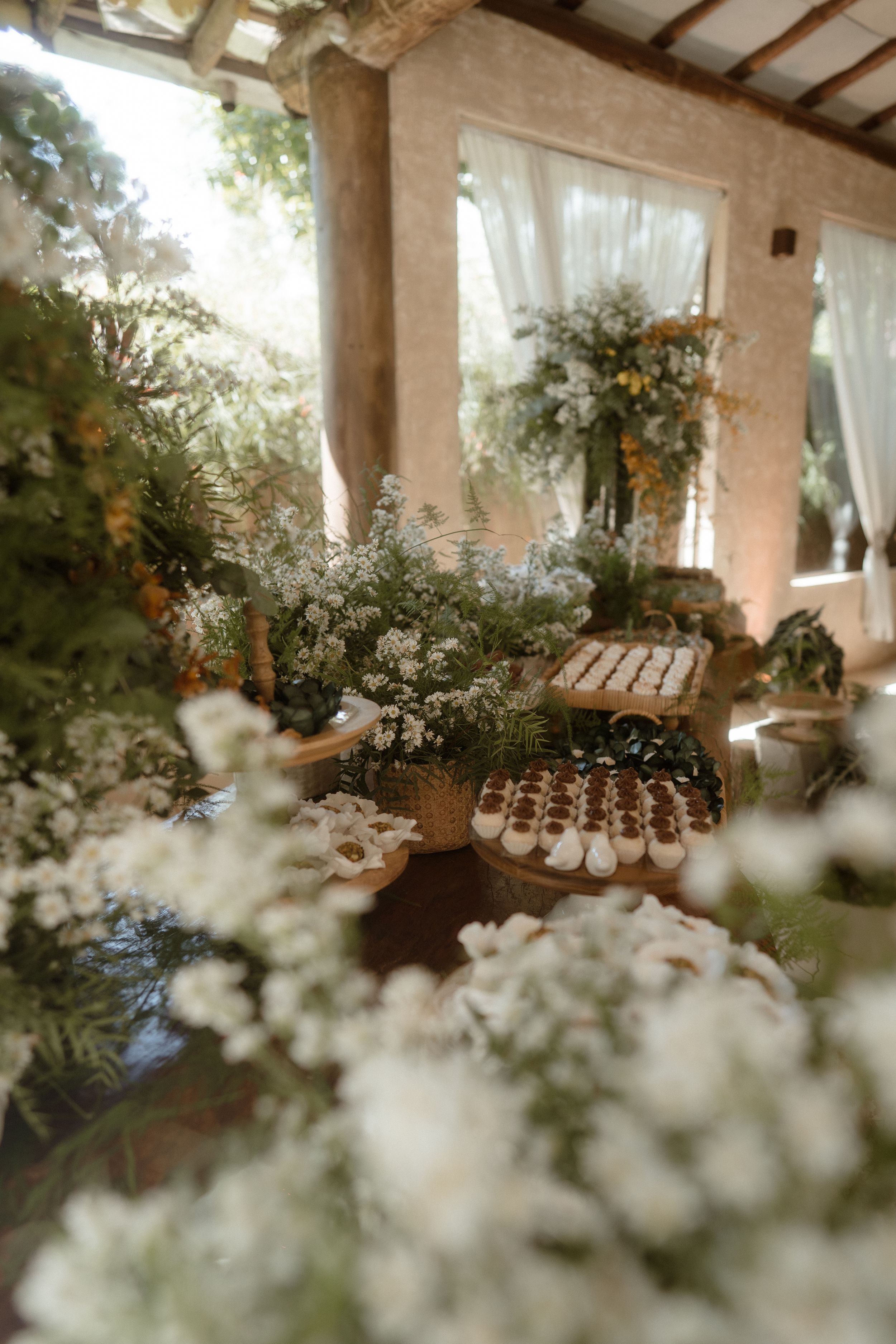 Rustic wedding dessert display with white flowers and decorative elements under a covered patio.