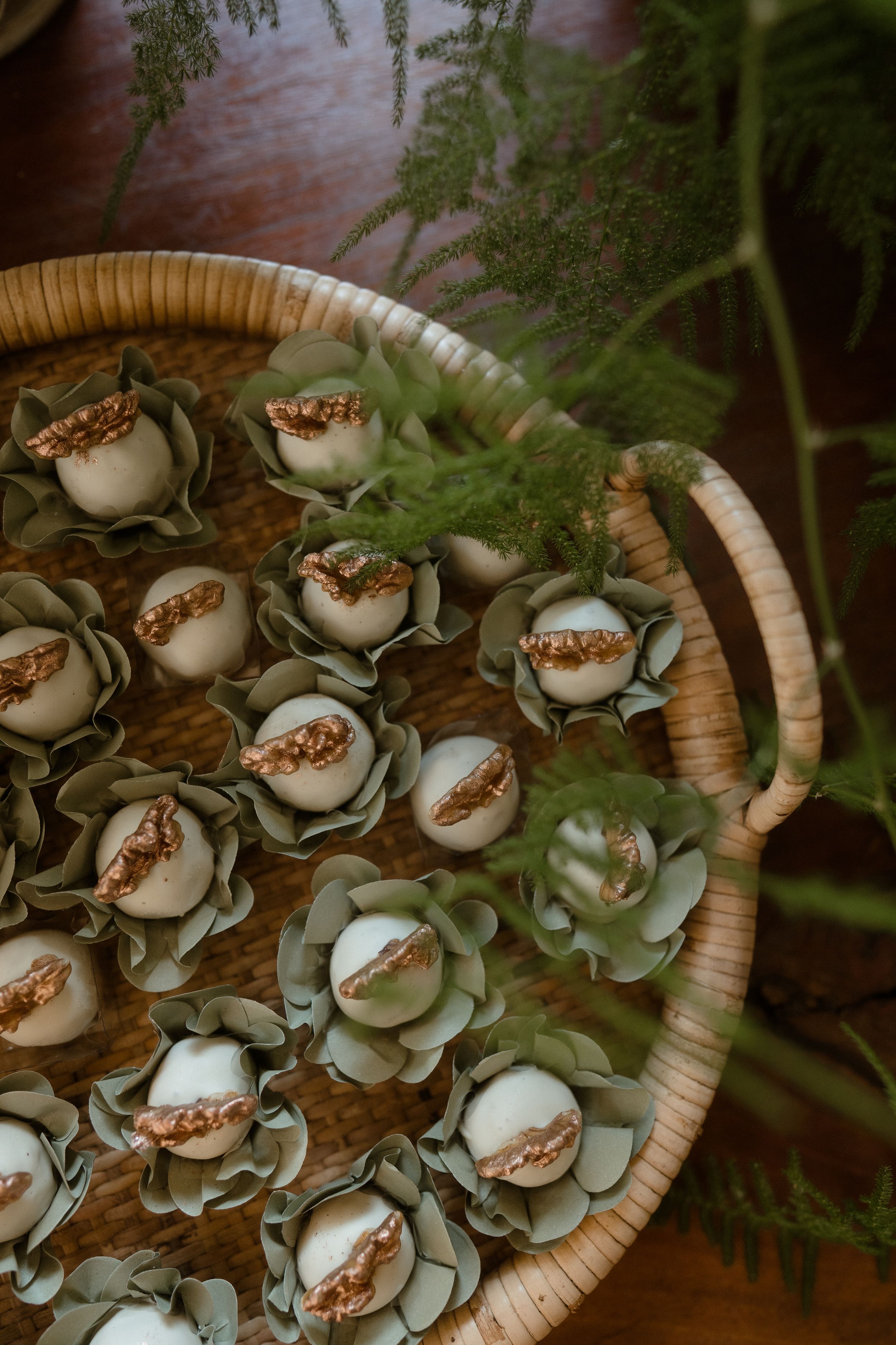 Decorative white flower-shaped desserts arranged in a woven basket with greenery.
