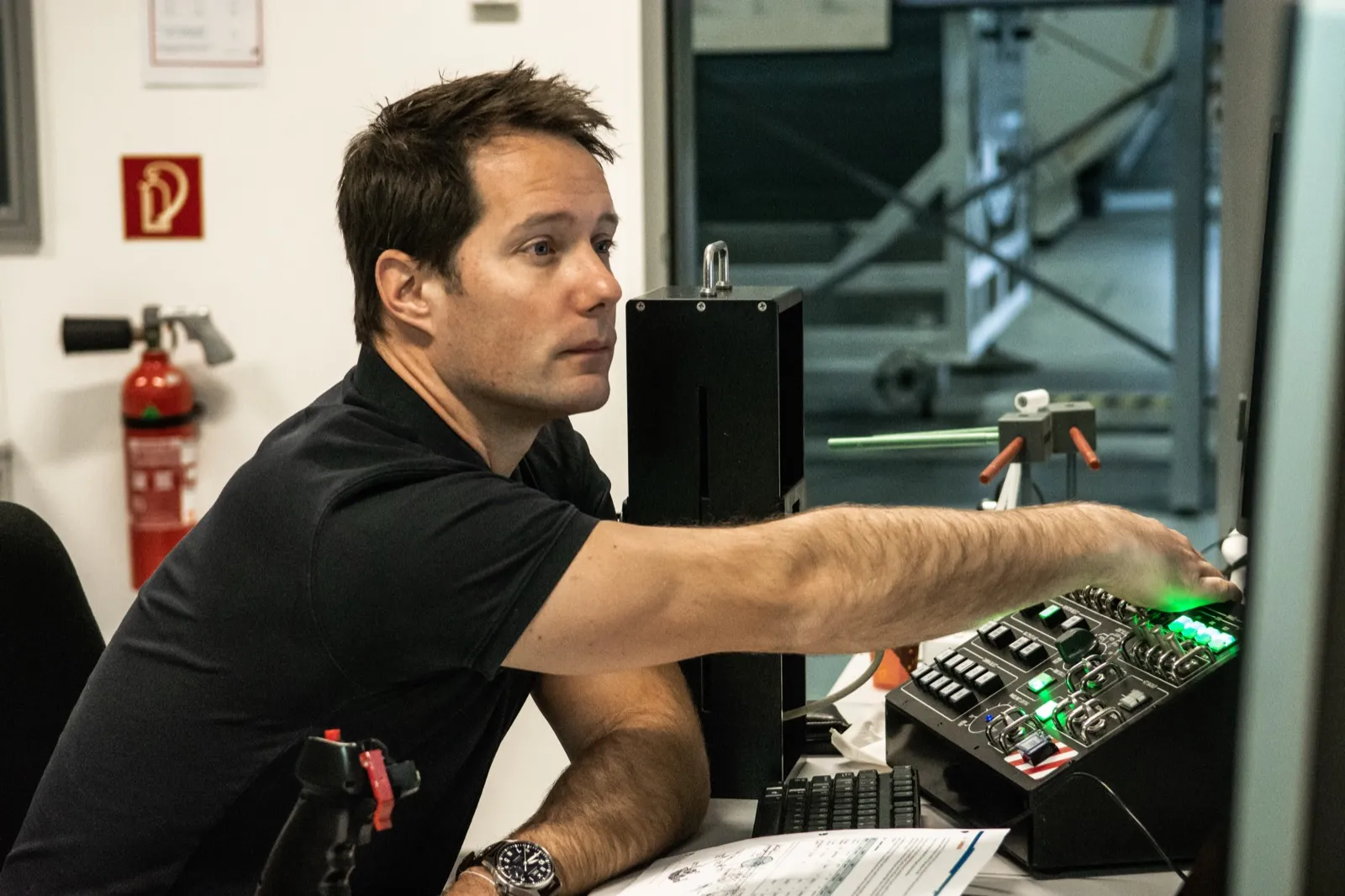 Un homme pointe un élément électronique sur un poste de travail.