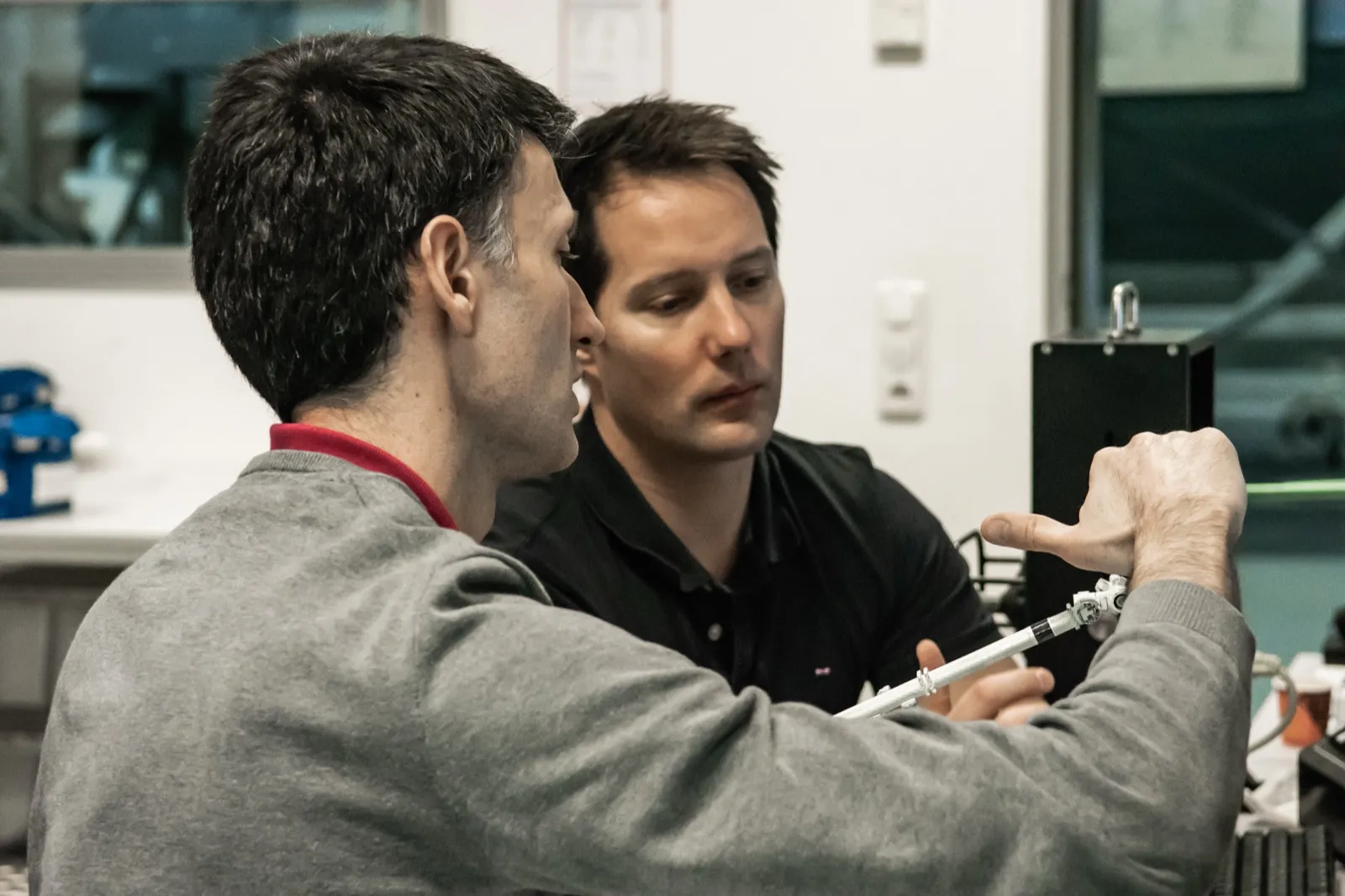 Deux hommes concentrés, en discussion technique dans un environnement de travail.
