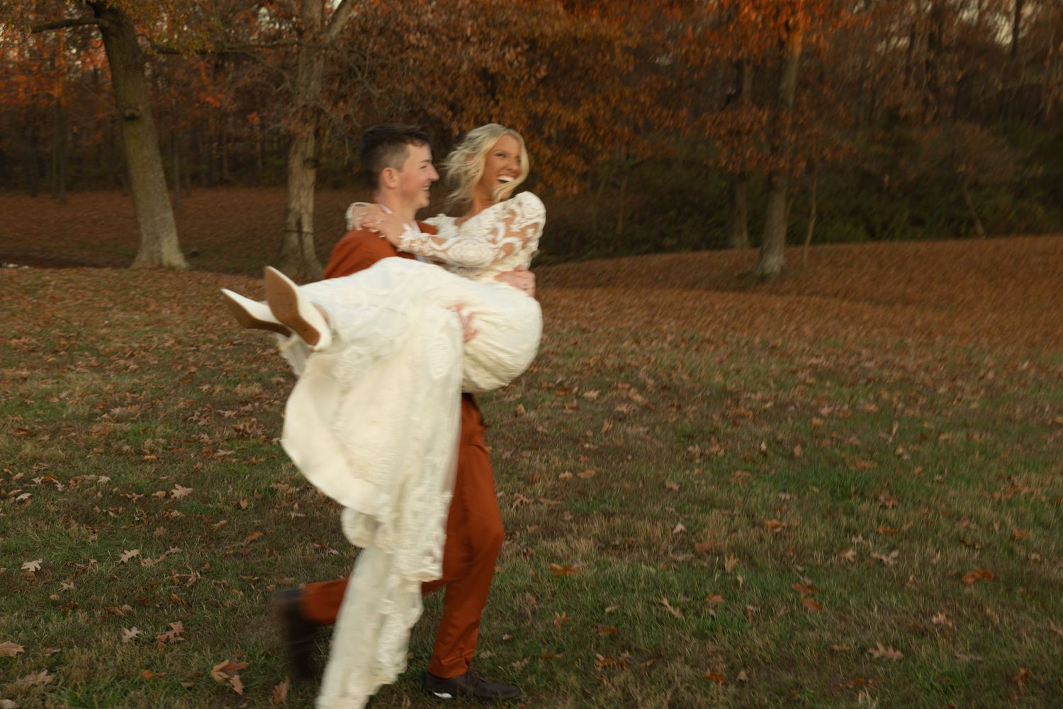 A joyful moment captured in autumn as a couple celebrates in formal attire among fall foliage.