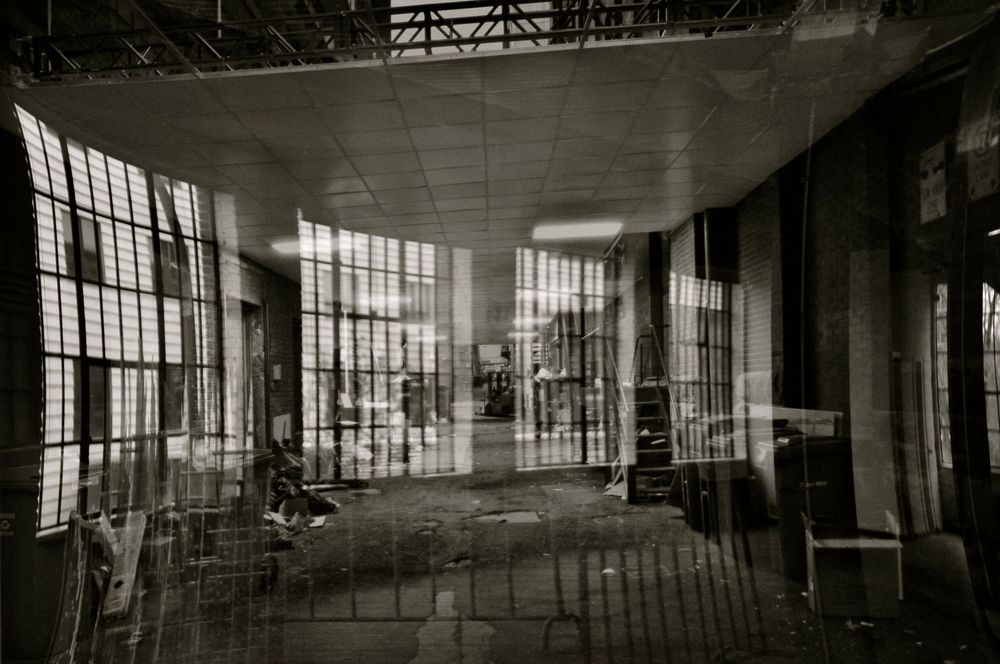 Abandoned interior of historic building with large industrial windows and empty space shows decay and architectural details.