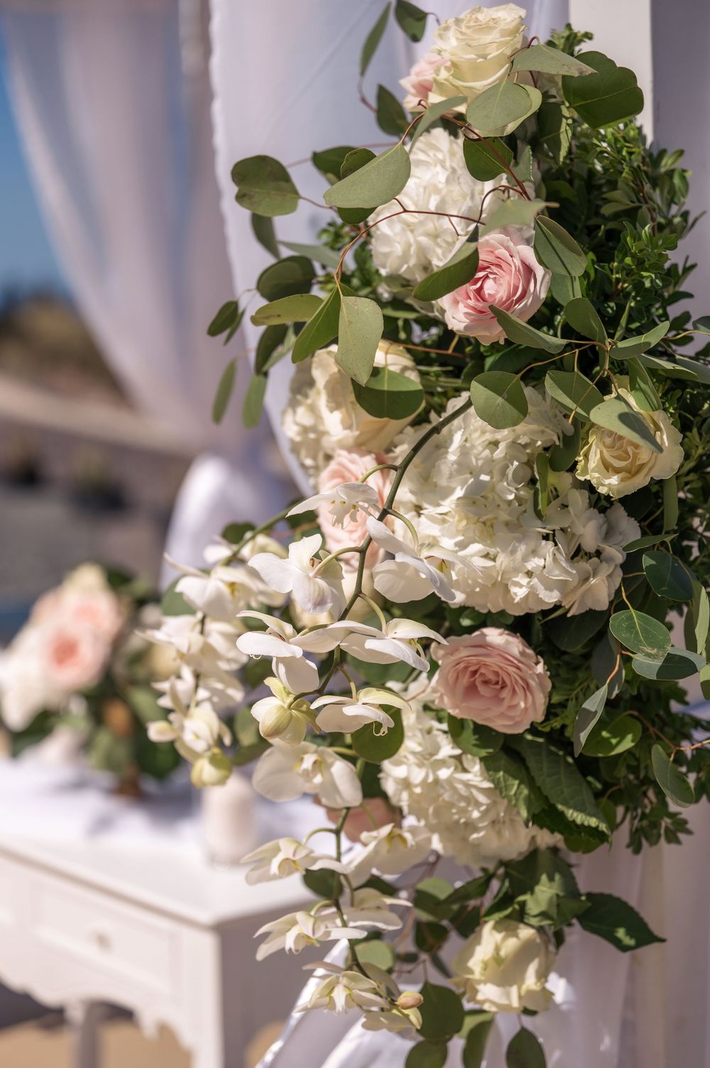 Delicate white and pink roses with greenery arranged in an elegant wedding floral decoration.