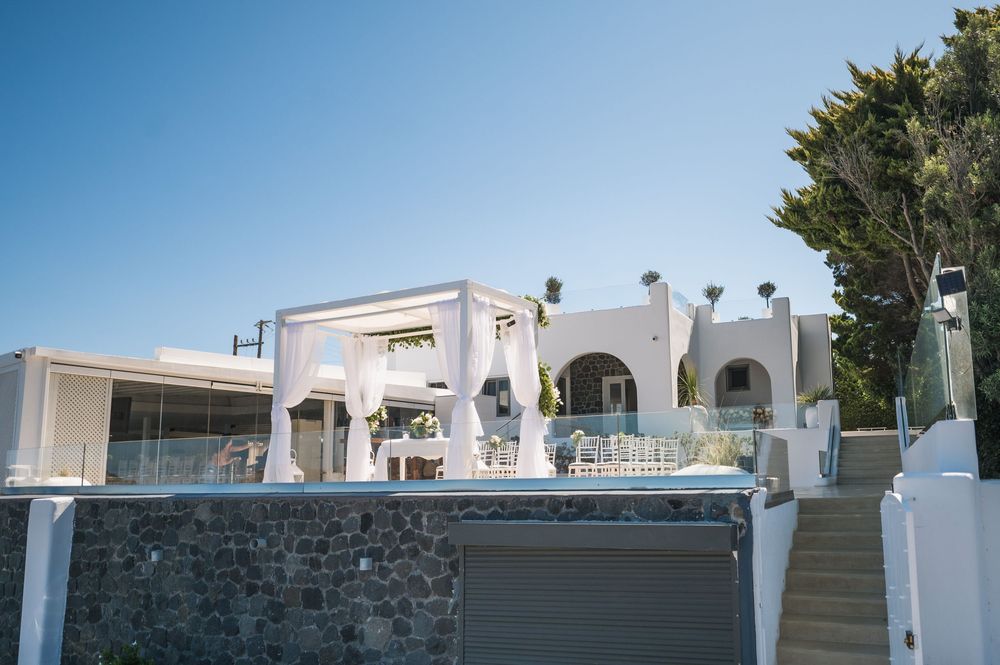 Elegant white Mediterranean villa with stone walls and arched architecture against bright blue sky in luxury resort setting.