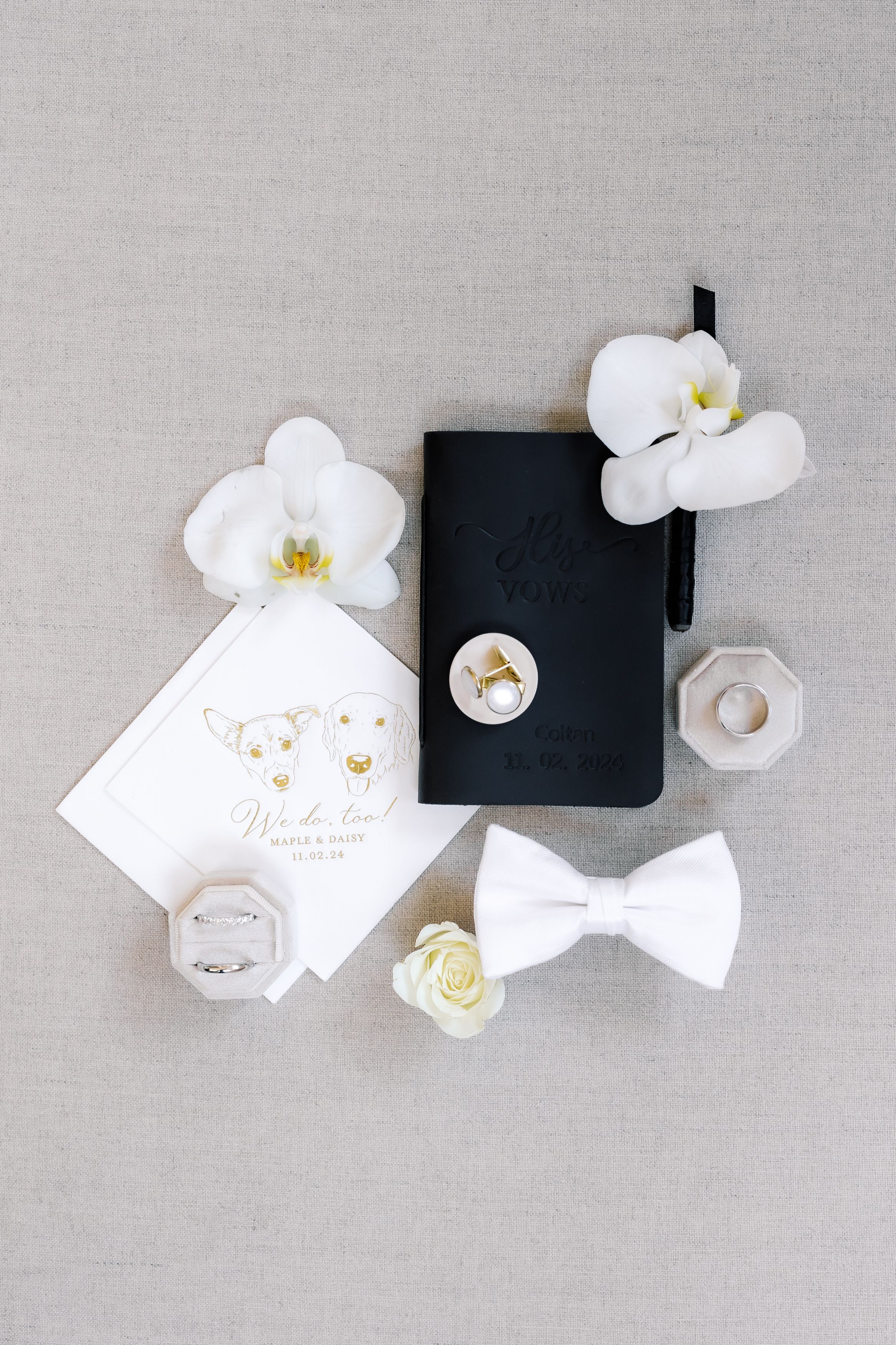 White orchids and small decorative items arranged in a minimalist flat lay composition on a light gray linen background.