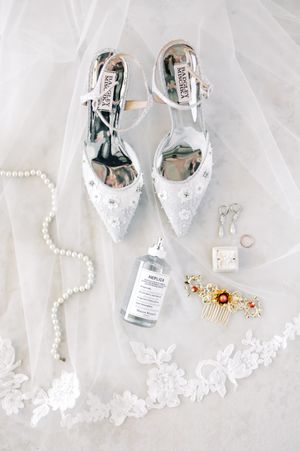 Wedding accessories including silver heels, pearl necklace, and lace details on white tulle.