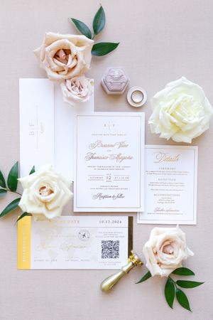 Elegant wedding invitation suite with white roses and gold accents on light background.