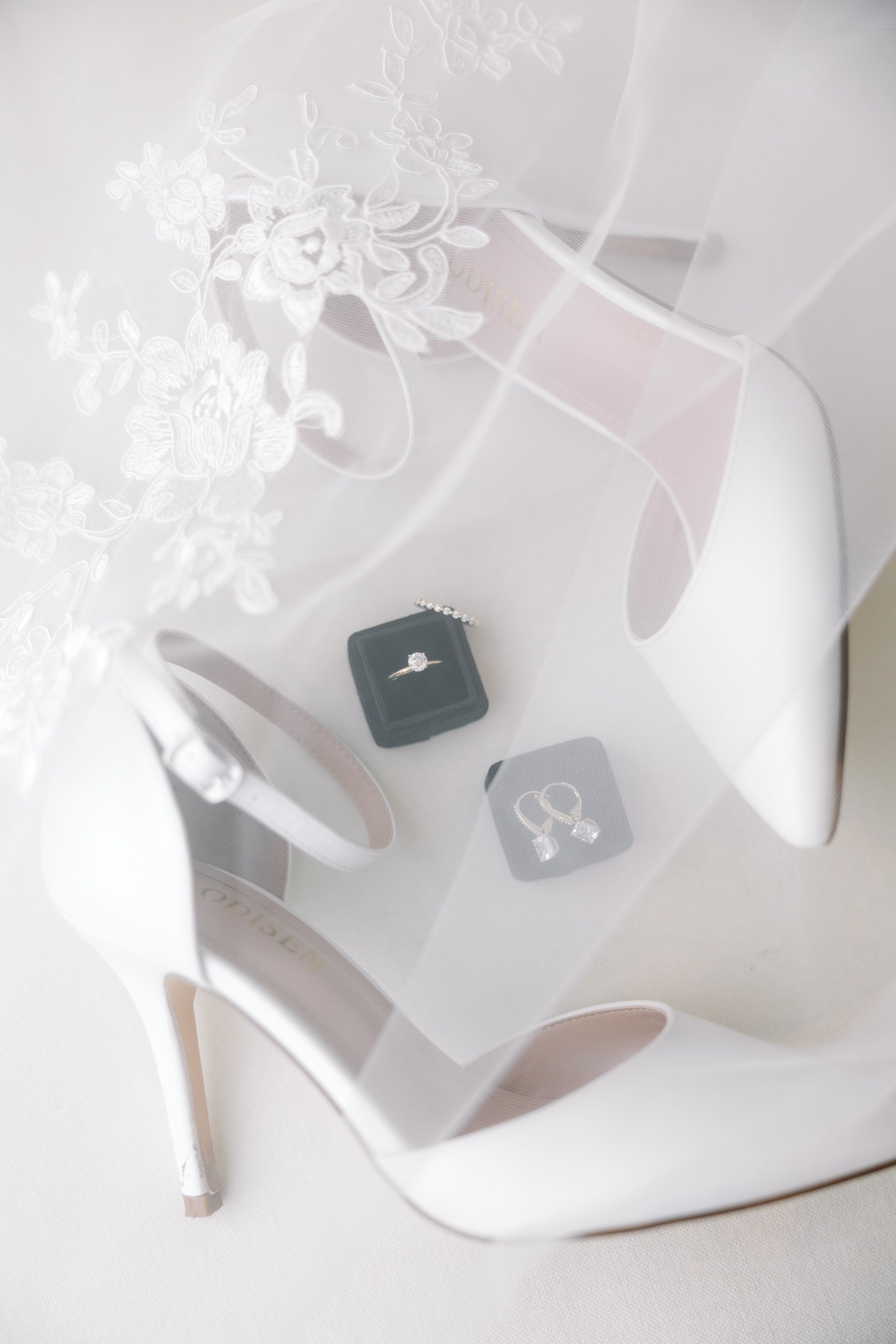 White bridal heels and accessories arranged on light grey background.