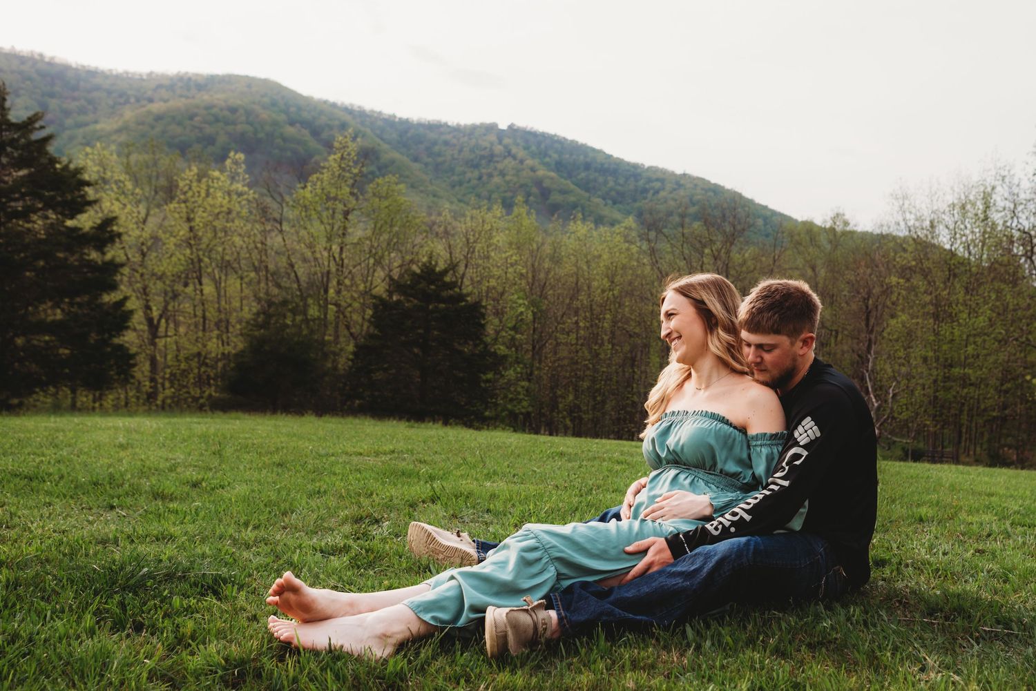 Intimate portrait of couple sitting together in mountain field at sunset.