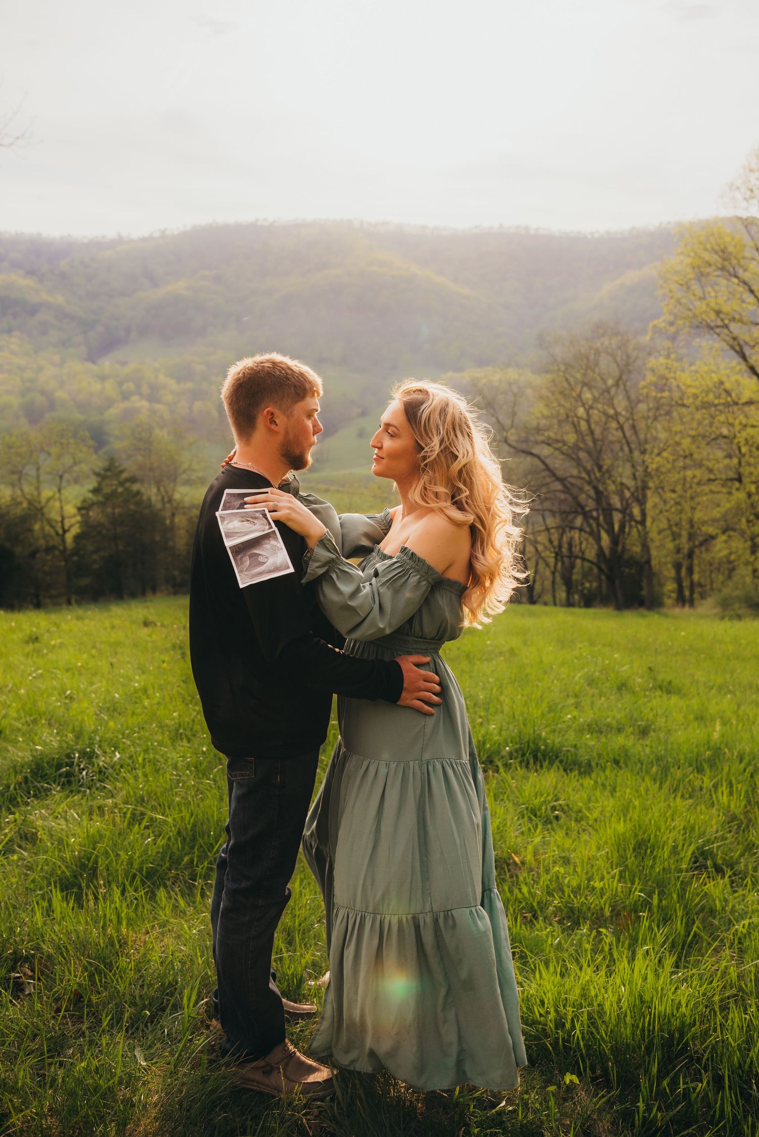 Romantic maternity photos captured in a serene mountain meadow during golden hour.
