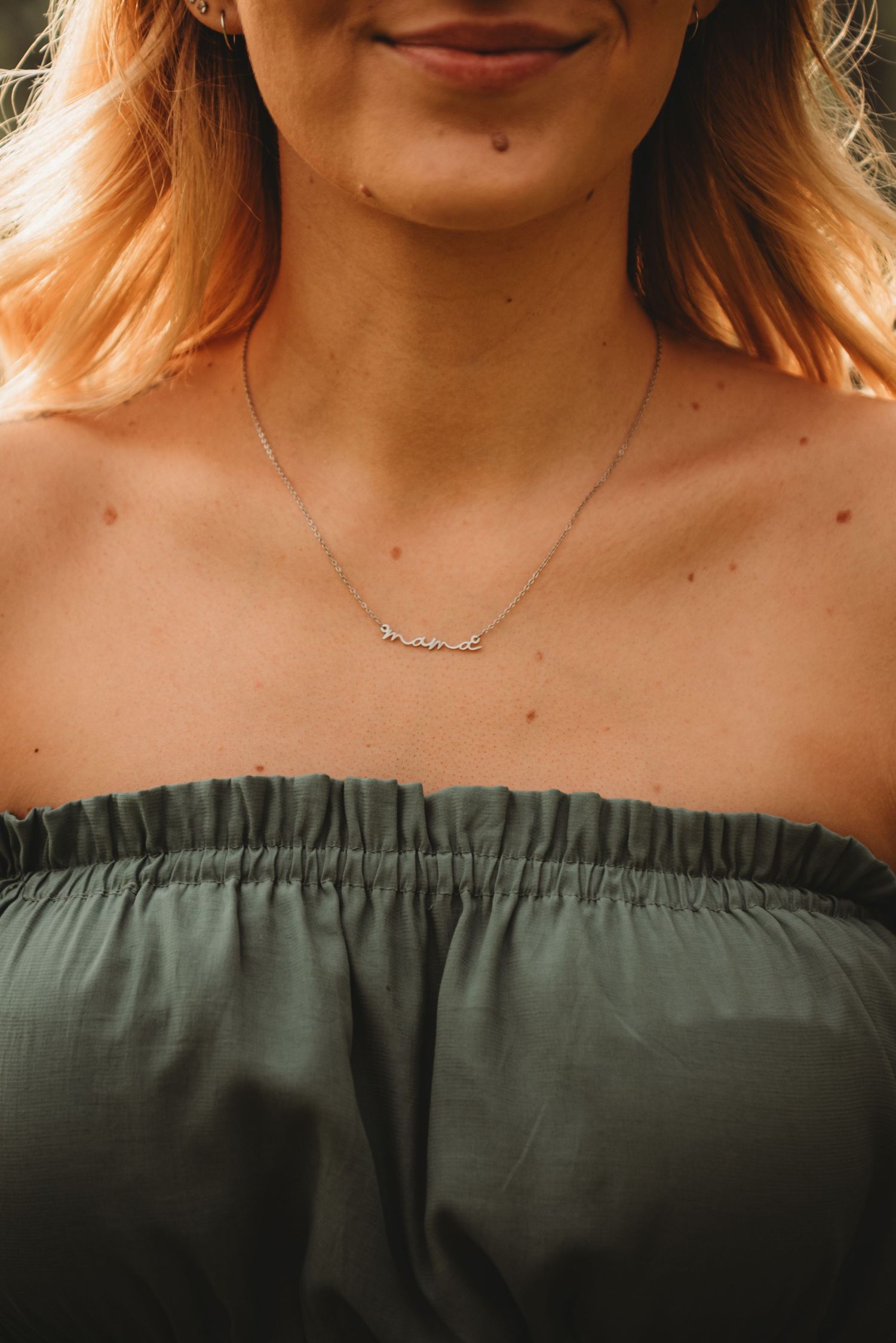 Detail shot of a sage green off-shoulder maternity dress neckline.