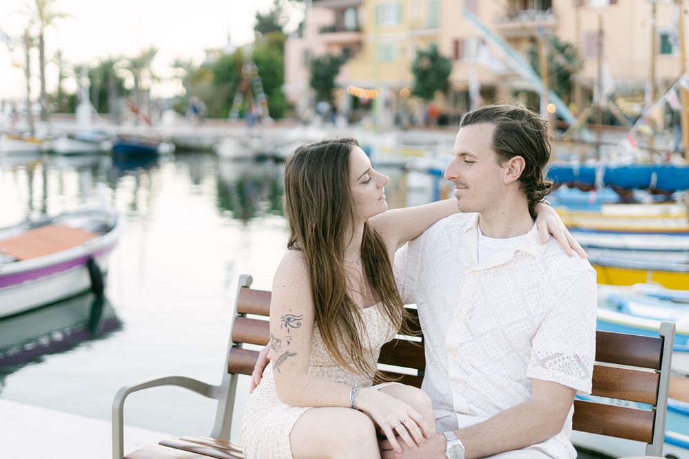 A romantic scene at a marina with waterfront boats and buildings in the background.