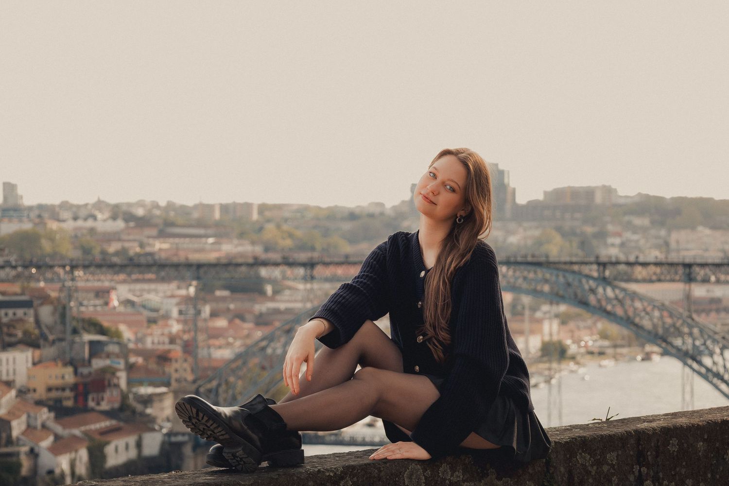 Woman in yellow dress poses on rooftop overlooking Porto's cityscape and bridge.