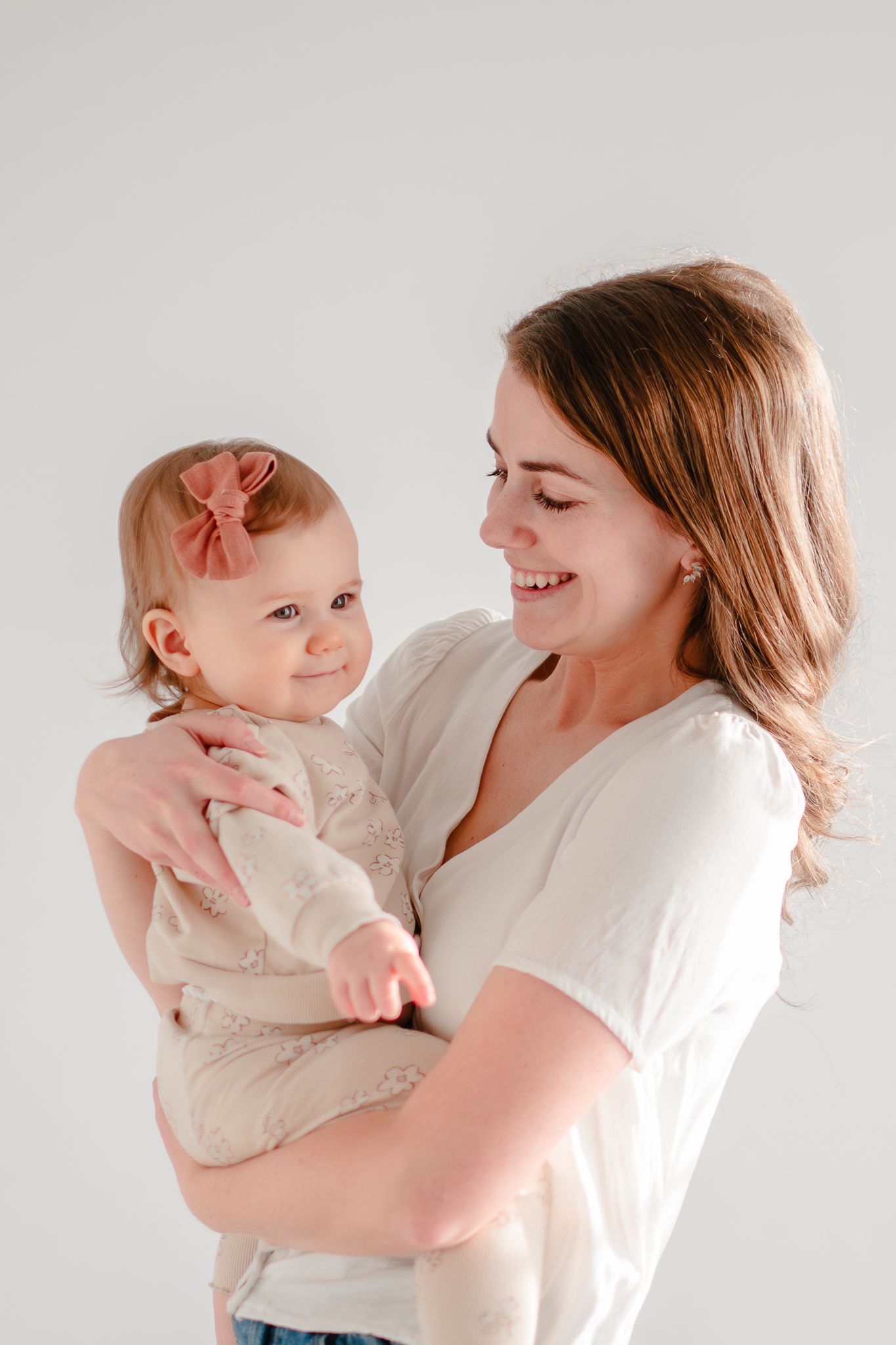 A joyful moment shared between parent and baby in matching white outfits against a light background.