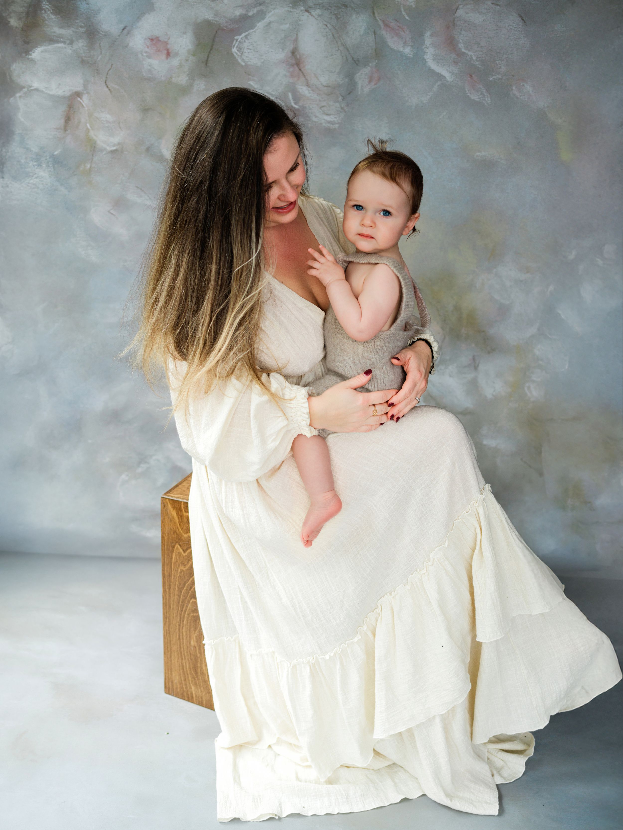 Portrait in white flowy dress with soft gray studio backdrop while sitting on wooden block in Bellevue.