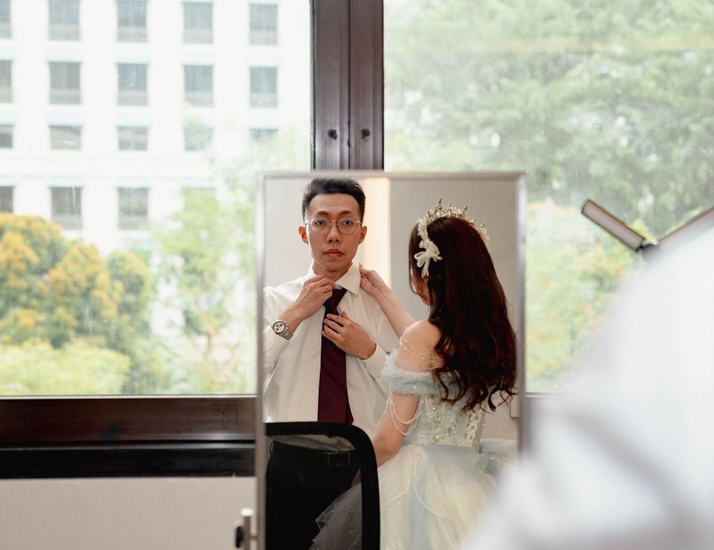 A bride and groom share a playful moment near a window during their wedding celebration.