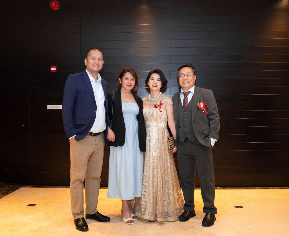 A group of four people pose together at a formal event, wearing elegant attire including a gold gown and suits.