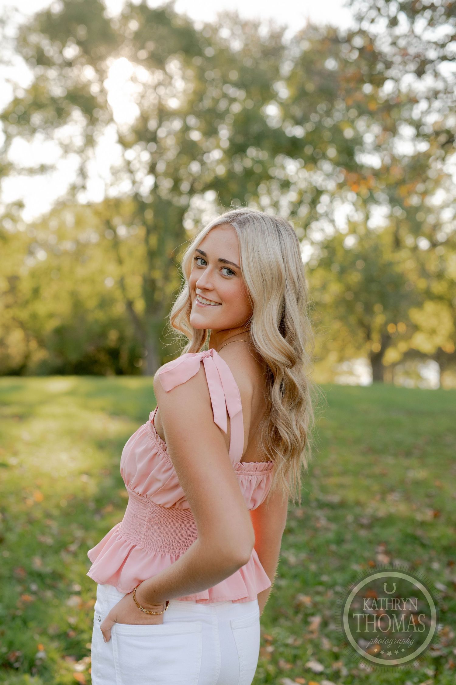 Side profile portrait with pink ruffle top against golden hour lighting and trees.