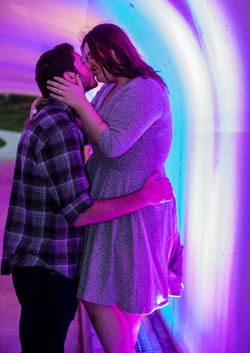 A romantic couple embraces in a tender moment against a backdrop of swirling purple and blue lights.