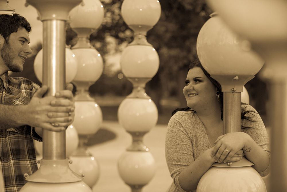 A vintage sepia-toned photograph showing two people chatting beside ornate white balustrades on a porch.