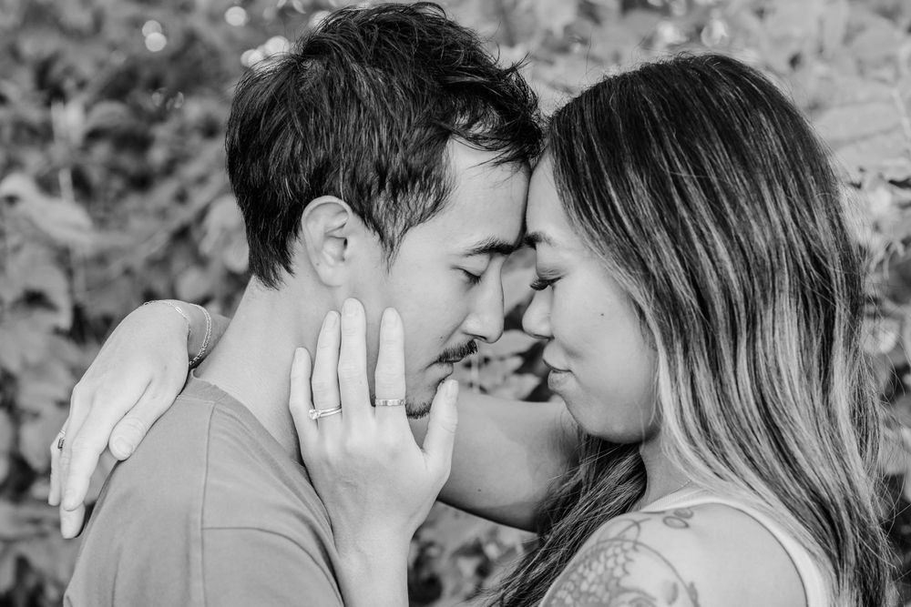A tender black and white close-up of a romantic couple sharing an intimate moment outdoors.