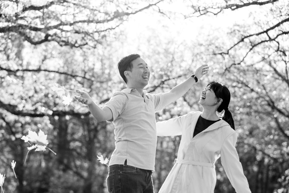 A couple shares a joyful moment together while dancing under blooming cherry blossom trees on a spring day.