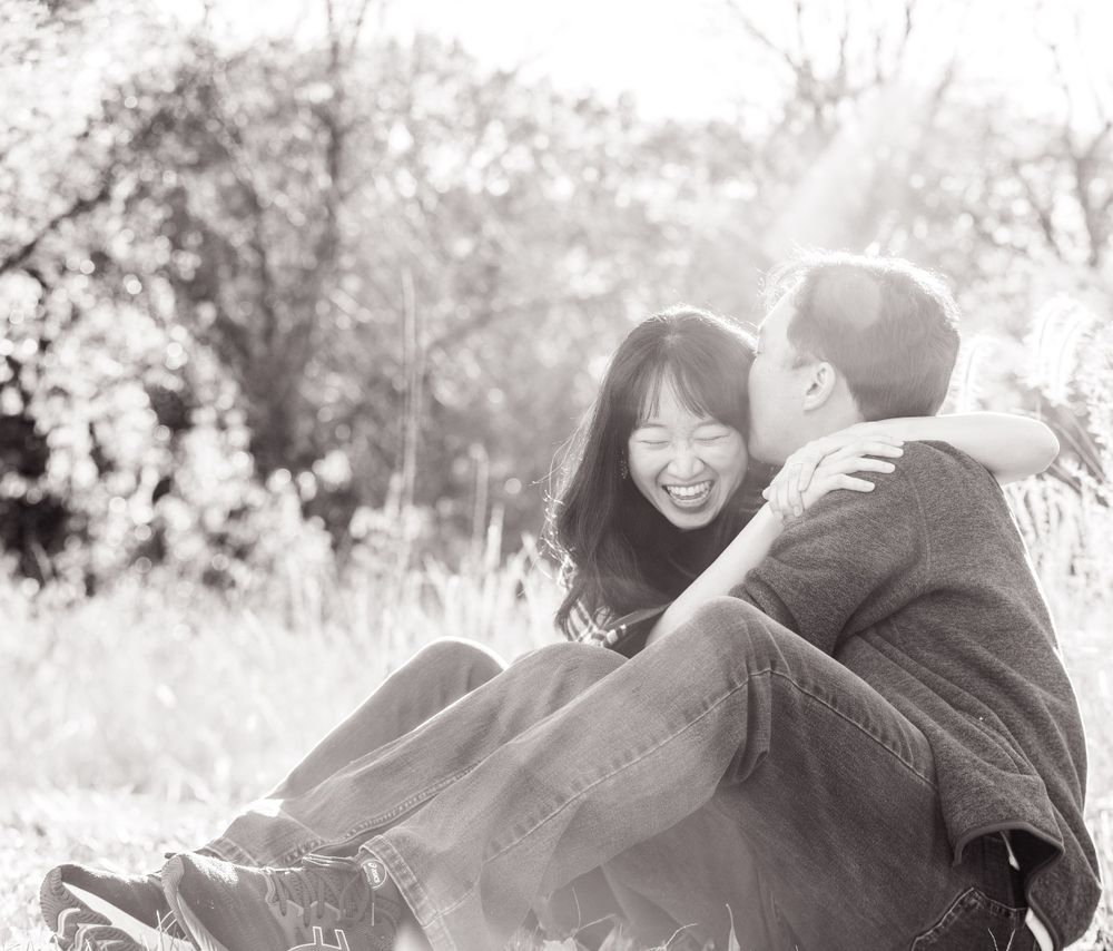 A happy couple shares a tender moment sitting together outdoors in black and white photography.