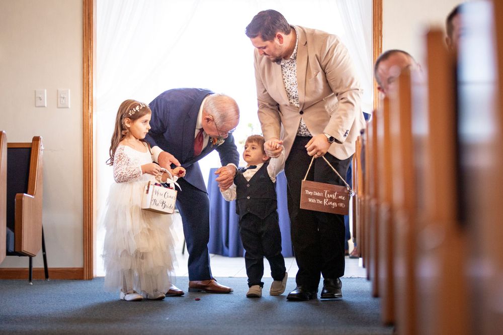 Adults and children gather in a church hallway before a ceremony, wearing formal attire.  Iowa City wedding photographer.